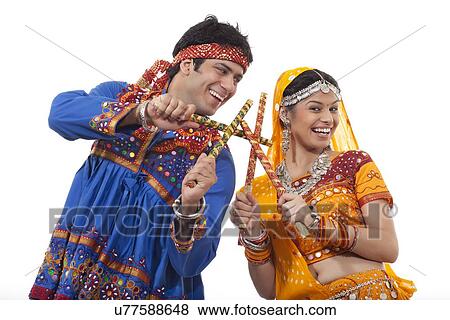 Happy young couple performing Dandiya Raas over white background View Large Photo Image Stock Photo - Happy young couple performing Dandiya Raas over white background. Fotosearch