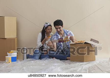 Stock Photo - Happy young couple reading magazine together at their new home . Fotosearch