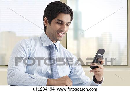 Happy young male executive reading text message View Large Photo Image Picture - Happy young male executive reading text message . Fotosearch