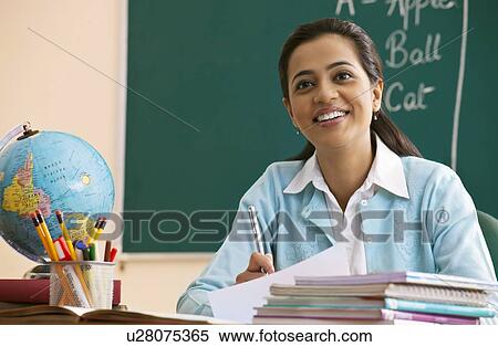 Happy young teacher looking away at desk View Large Photo Image Stock Photography - Happy young teacher looking away at desk . Fotosearch
