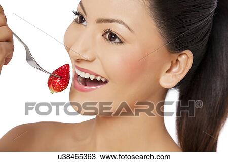Stock Image - Happy young woman eating strawberry . Fotosearch