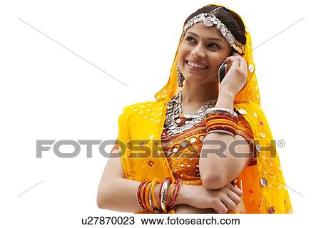 Happy young woman in traditional wear using mobile phone against white background View Large Photo Image Stock Image - Happy young woman in traditional wear using mobile phone against white background. Fotosearch