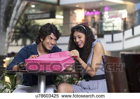 Happy young woman looking inside bag with man smiling View Large Photo Image Stock Photography - Happy young woman looking inside bag with man smiling . Fotosearch