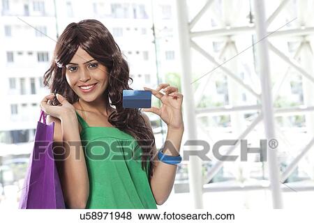 Stock Photo - Happy young woman showing her credit card . Fotosearch