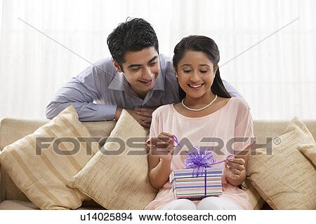 Happy young woman unwrapping the gift at home View Large Photo Image Picture - Happy young woman unwrapping the gift at home . Fotosearch