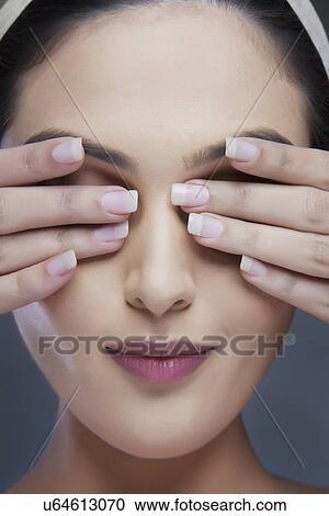 Head shot of a beautiful woman covering eyes with hands over colored background View Large Photo Image Stock Image - Head shot of a beautiful woman covering eyes with hands over colored background . Fotosearch