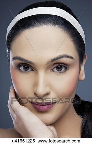 Head shot portrait of a beautiful young woman touching her face over colored background View Large Photo Image Stock Photography - Head shot portrait of a beautiful young woman touching her face over colored background . Fotosearch