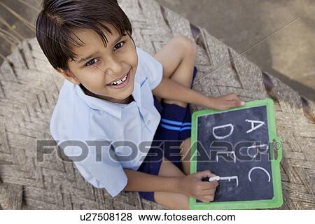 Stock Photo - High angle view of a little school boy writing on slate . Fotosearch
