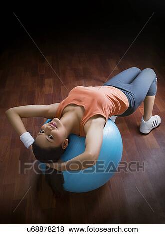 High angle view of young woman balancing on a fitness ball with hands behind head View Large Photo Image Stock Photo - High angle view of young woman balancing on a fitness ball with hands behind head . Fotosearch