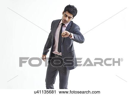 Hurried young businessman checking time over white background View Large Photo Image Stock Image - Hurried young businessman checking time over white background . Fotosearch