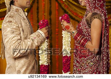 Indian bride and groom holding garlands View Large Photo Image Stock Photo - Indian bride and groom holding garlands . Fotosearch