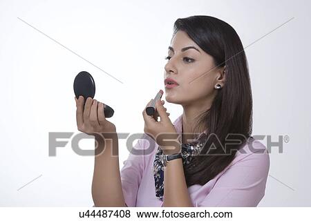 Indian businesswoman applying lipstick against white background View Large Photo Image Stock Photo - Indian businesswoman applying lipstick against white background. Fotosearch