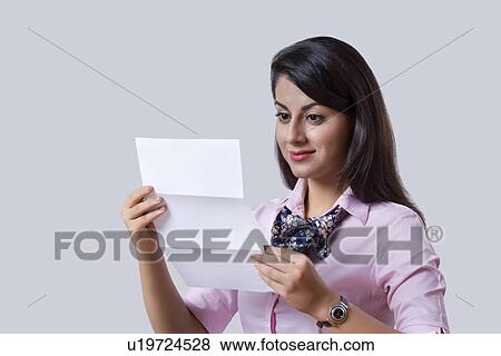 Stock Photo - Indian businesswoman smiling while reading document over white background. Fotosearch