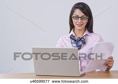 Stock Photo - Indian businesswoman working on laptop at desk in office. Fotosearch