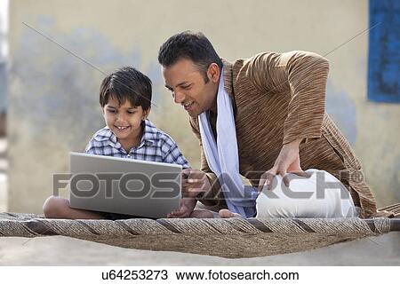 Stock Image - Indian father and son using laptop . Fotosearch