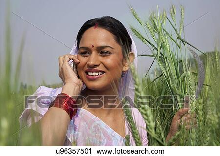 Indian female farm worker looking away while talking on mobile phone View Large Photo Image Stock Image - Indian female farm worker looking away while talking on mobile phone . Fotosearch