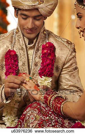 Indian groom putting a wedding ring on a bride View Large Photo Image Stock Photograph - Indian groom putting a wedding ring on a bride . Fotosearch
