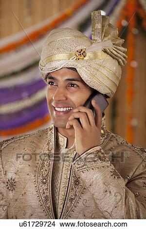 Indian groom talking on a mobile phone View Large Photo Image Picture - Indian groom talking on a mobile phone . Fotosearch