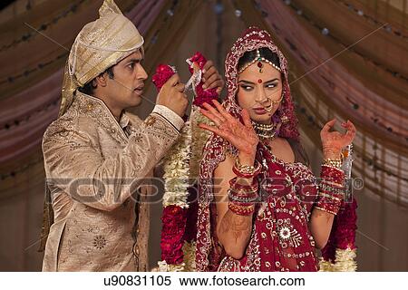 Indian groom trying to put a garland on his bride View Large Photo Image Stock Photography - Indian groom trying to put a garland on his bride . Fotosearch