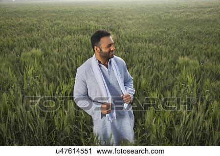 Indian man looking away while standing in a field View Large Photo Image Stock Image - Indian man looking away while standing in a field . Fotosearch