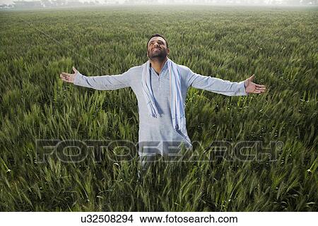 Indian man standing in field with arms out View Large Photo Image Picture - Indian man standing in field with arms out . Fotosearch