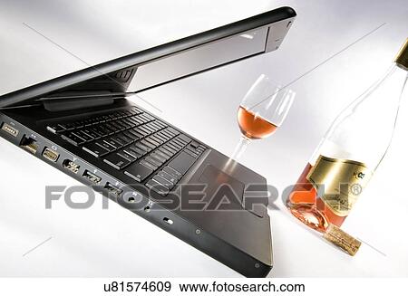 Stock Photo - Laptop with a glass and a bottle . Fotosearch