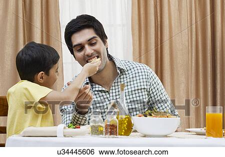 Little boy feeding piece of pizza to father at restaurant View Large Photo Image Stock Photograph - Little boy feeding piece of pizza to father at restaurant . Fotosearch