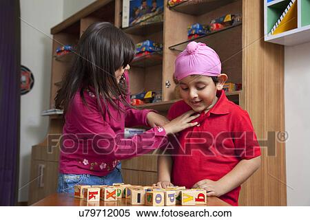Little boy looking at wooden toy blocks while standing with sister View Large Photo Image Stock Photography - Little boy looking at wooden toy blocks while standing with sister . Fotosearch