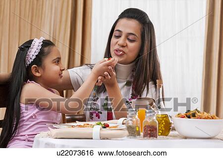 Little girl feeding her mother piece of pizza at restaurant View Large Photo Image Stock Photograph - Little girl feeding her mother piece of pizza at restaurant . Fotosearch