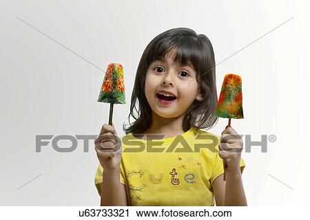 Stock Image - Little girl holding two ice lollies . Fotosearch