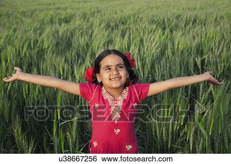 Little girl standing with arms out in a wheat field View Large Photo Image Stock Photograph - Little girl standing with arms out in a wheat field . Fotosearch