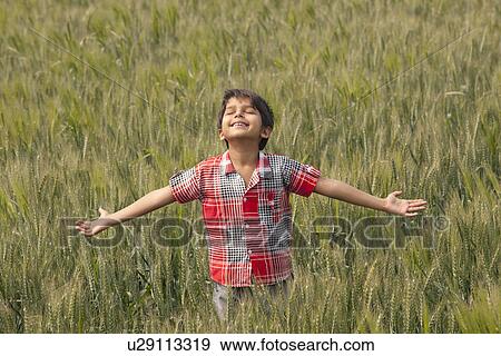 Stock Photo - Little toddler standing in wheat field with arms out . Fotosearch