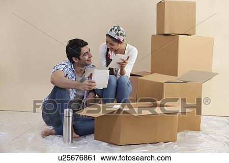 Stock Image - Loving young couple looking at each other while holding photographs . Fotosearch