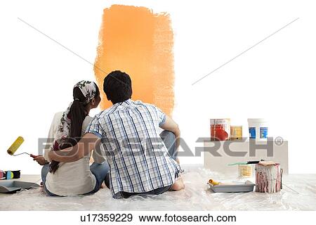 Loving young couple looking at sample paint together on wall View Large Photo Image Stock Photo - Loving young couple looking at sample paint together on wall . Fotosearch