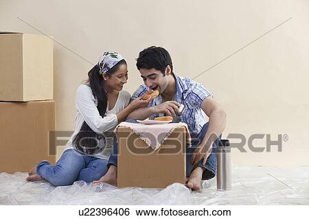 Loving young couple sharing food together at their new home View Large Photo Image Stock Photograph - Loving young couple sharing food together at their new home . Fotosearch