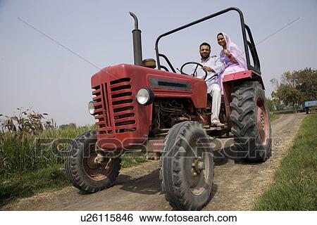 Stock Photograph - Low angle view of an Indian couple sitting in a tractor . Fotosearch