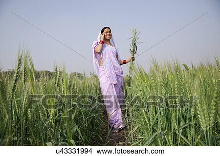 Picture - Low angle view of Indian female farm worker talking on mobile phone . Fotosearch
