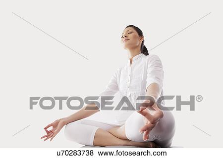 Stock Photo - Low angle view of young woman sitting in lotus position . Fotosearch