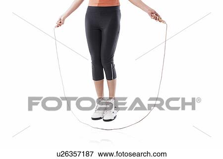 Low section of a woman exercising with jump rope over white background View Large Photo Image Stock Photo - Low section of a woman exercising with jump rope over white background . Fotosearch