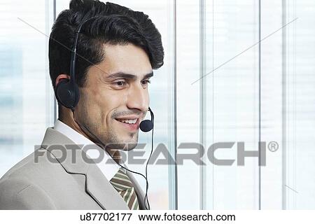 Stock Photo - Male customer service representative looking away in office. Fotosearch