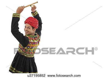 Stock Image - Male dandiya dancer dancing with sticks . Fotosearch