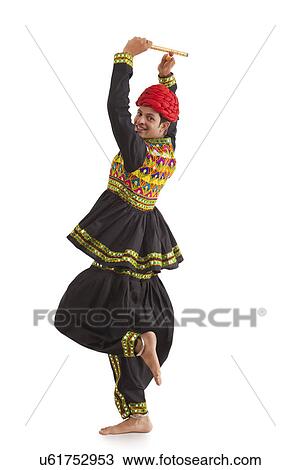 Stock Image - Male dandiya dancer dancing with sticks . Fotosearch