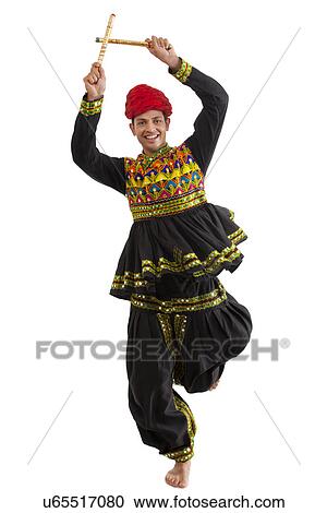 Stock Image - Male dandiya dancer dancing with sticks . Fotosearch