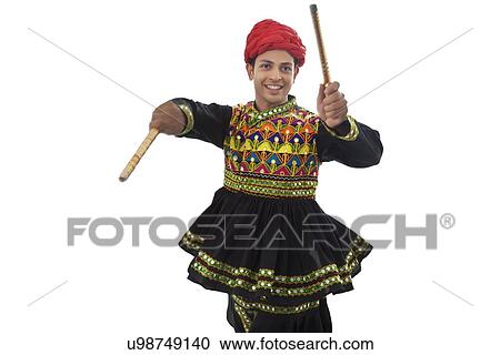 Stock Image - Male dandiya dancer dancing with sticks . Fotosearch