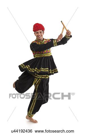 Stock Photograph - Male dandiya dancer dancing with sticks . Fotosearch