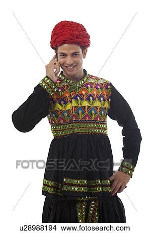 Male dandiya dancer talking on a mobile phone View Large Photo Image Picture - Male dandiya dancer talking on a mobile phone . Fotosearch