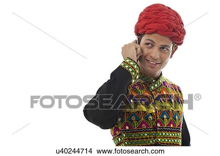 Picture - Male dandiya dancer talking on a mobile phone . Fotosearch