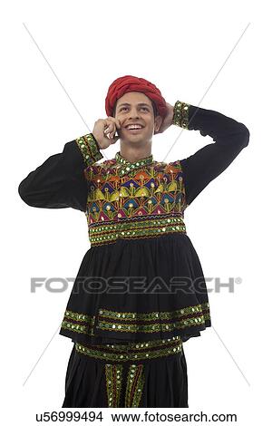 Male dandiya dancer talking on a mobile phone View Large Photo Image Picture - Male dandiya dancer talking on a mobile phone . Fotosearch