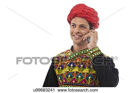 Stock Image - Male dandiya dancer talking on a mobile phone . Fotosearch