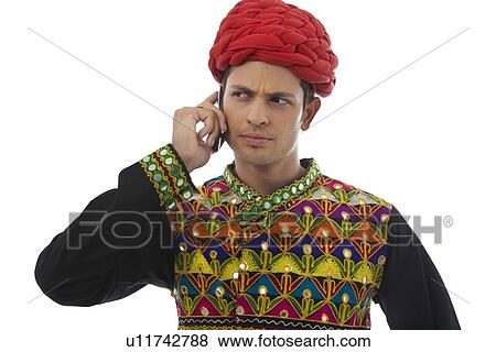 Male dandiya dancer talking on a mobile phone View Large Photo Image Stock Photo - Male dandiya dancer talking on a mobile phone . Fotosearch